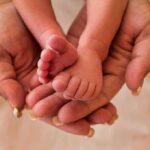 Adult hands cradling a newborn's tiny feet