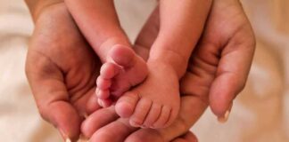 Adult hands cradling a newborn's tiny feet