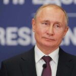 Kremlin’s Fixers Lock Down Mariupol Profits man in suit speaking at a podium