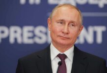 Kremlin’s Fixers Lock Down Mariupol Profits man in suit speaking at a podium