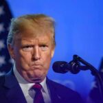 Donald Trump at a podium with U.S. flags in the background
