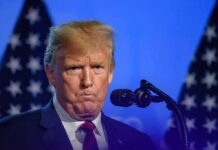 Hoax Alert: Trump Torches Iran Relief Claim Donald Trump at a podium with U.S. flags in the background