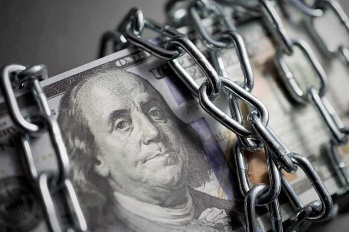 shutterstock_1403829620-1 US dollar bills wrapped in metal chains