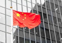 Chinese flag waving against glass office building