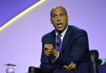 Booker Explodes: Trump ‘Criminal’ Warning Cory Booker speaking on stage in a suit and tie