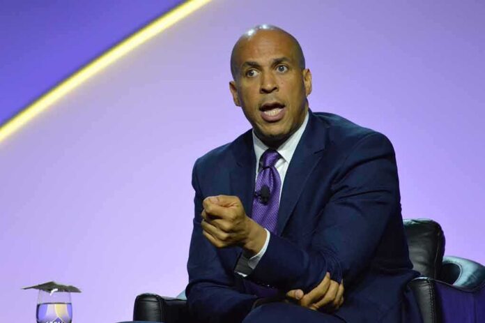 shutterstock_1462049714 Cory Booker speaking on stage in a suit and tie