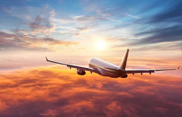 Airplane flying above clouds at sunset