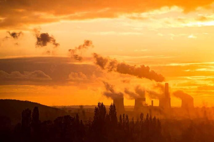 Power plant cooling towers emit smoke at sunset