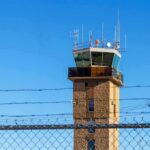 LaGuardia Shock: Time-Card Fraud Tied To Deadly Collision Airport control tower behind chain-link and barbed-wire fence