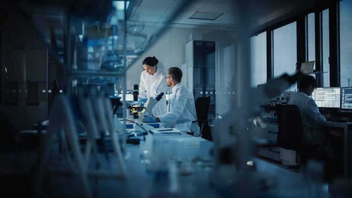 shutterstock_1884612574 Scientists working in a dim laboratory