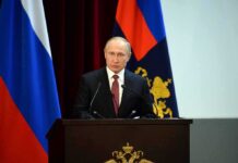 speaker at podium with flags in background