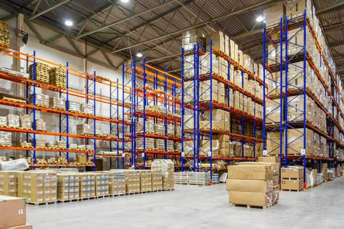 Warehouse aisles with tall blue and orange pallet racks filled with boxes