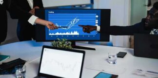 Business team pointing at stock chart on monitor during meeting