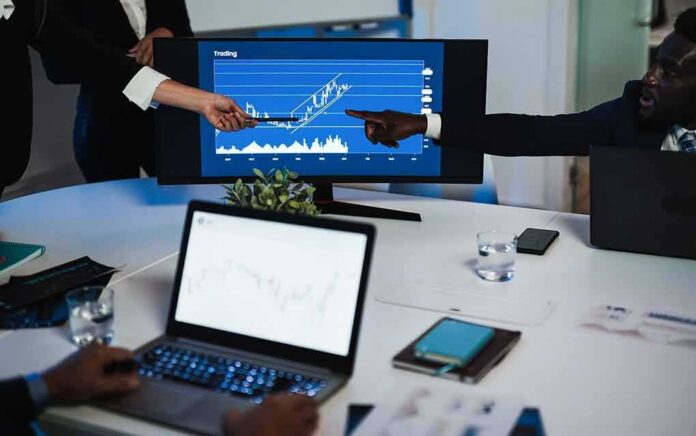 Business team pointing at stock chart on monitor during meeting