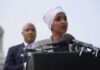 Ilhan Omar speaking at a podium with André Carson standing behind