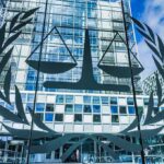 Sanctions Hammer ICC – Trump Chokes Money Pipeline Scales of justice emblem on glass facade of modern office building