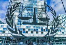 Sanctions Hammer ICC – Trump Chokes Money Pipeline Scales of justice emblem on glass facade of modern office building