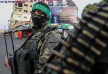 armed person in camouflage and face covering on a city street