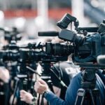Incumbent Crushed — Agenda Lurches Left Broadcast cameras on tripods at a press event