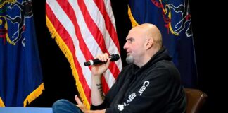 Man in a hoodie speaking into a microphone on stage