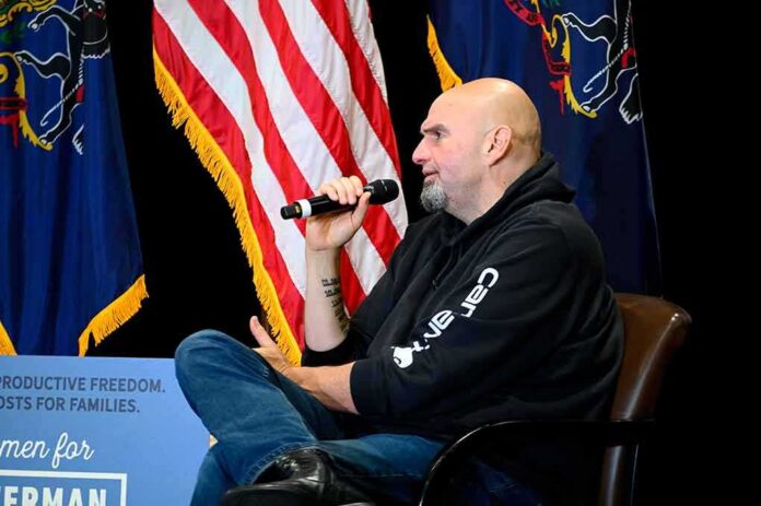 Man in a hoodie speaking into a microphone on stage