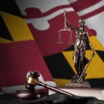 Lady Justice statue with gavel and book before a colorful flag backdrop