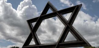 Large Star of David sculpture in a park under cloudy sky