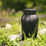 Black urn placed on greenery outdoors