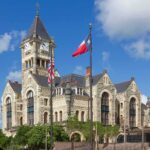 Taxpayer Cash Halted — Deportation Defense Frozen Historic stone courthouse with clock tower and flags
