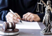 TRICARE Scam Exposed – Veterans Exploited Judge writing at desk with gavel and Lady Justice statue