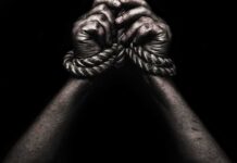 CNN Erupts: Capitalism Called White Supremacy Hands bound with rope against a dark background