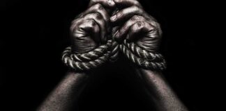 Hands bound with rope against a dark background