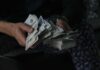 Massive Penalties Loom – Huntington Beach Cornered Hands holding large stacks of U.S. dollar bills