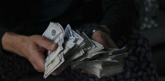 Hands holding large stacks of U.S. dollar bills