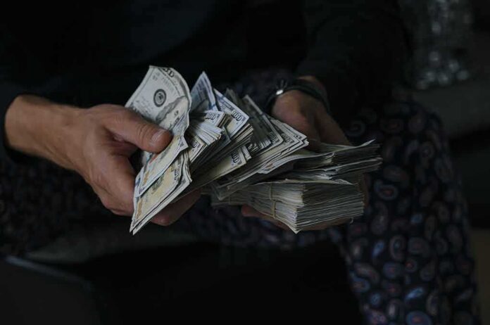 Hands holding large stacks of U.S. dollar bills