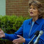 Lisa Murkowski speaking at an outdoor press conference with microphones in front