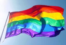 Rainbow pride flag waving against a clear blue sky