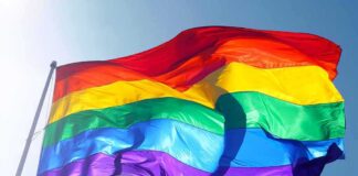 Rainbow pride flag waving against a clear blue sky