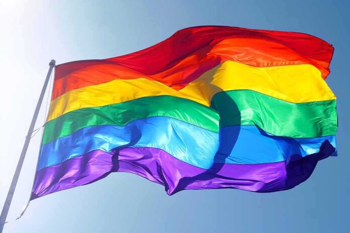 shutterstock_115334458-1 Rainbow pride flag waving against a clear blue sky