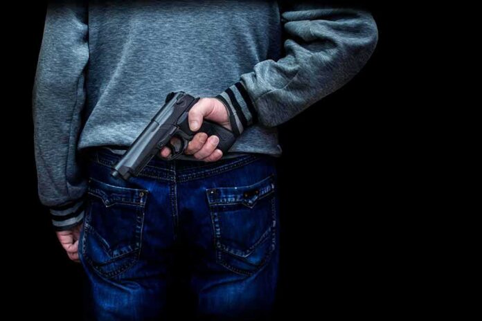 shutterstock_1218320314 person holding a handgun behind their back
