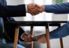 Minnesota’s $62M Refugee Machine – Churches Cash In Per Arrival? Two people shake hands while exchanging cash under a table