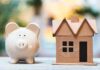 Piggy bank beside cardboard house model on a table
