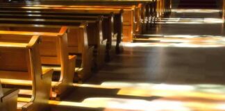 Wooden church pews with stained glass light on the aisle