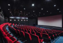 empty movie theater with red seats and large screen