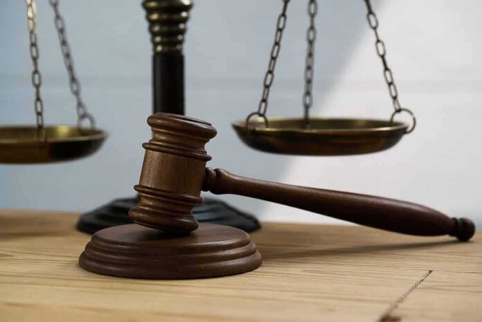 shutterstock_1335186209 Judge's gavel on block with scales of justice in background