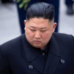 Kim Jong-chang in a black overcoat looking to the side