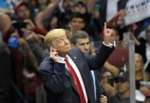 Donald Trump gestures with one hand raised at a crowded event