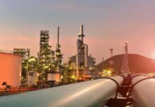 Iran War Windfall – Outrage Math Meets Empty Receipts Oil refinery with pipelines at sunset