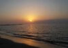 Sunset over calm sea with gentle waves on a sandy beach