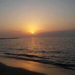 Housing Push Meets Ponto Backlash Sunset over calm sea with gentle waves on a sandy beach